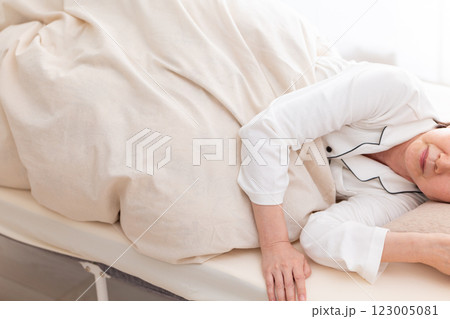 朝の寝室で熟睡する白いパジャマ姿のミドル女性 123005081