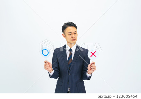 マルバツを持って迷うミドルエイジ男性ビジネスパーソン 123005454