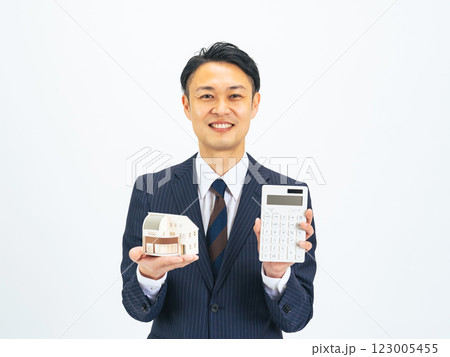 住宅模型と電卓を見せるミドルエイジ男性ビジネスパーソン 123005455