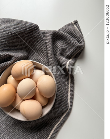 Fresh farm chicken eggs in bowl with kitchen towel on white background 123006052