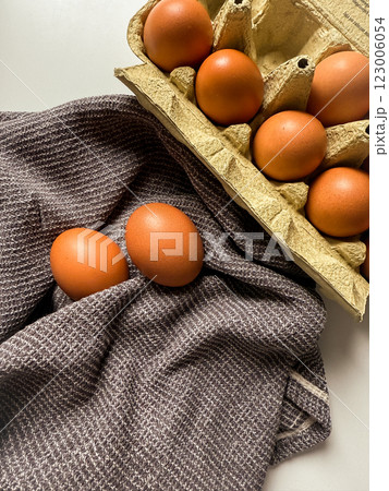 Brown chicken eggs in a paper tray and on kitchen towel Brown chicken eggs in a paper tray and on kitchen towel 123006054