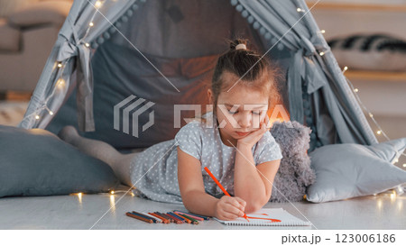 Conception of education. Cute little girl playing in the tent that is in the domestic room Conception of education. Cute little girl playing in the tent that is in the domestic room 123006186