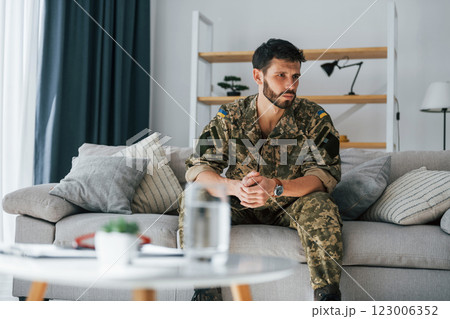 On the sofa. Post traumatic stress disorder. Soldier in uniform sitting indoors On the sofa. Post traumatic stress disorder. Soldier in uniform sitting indoors 123006352