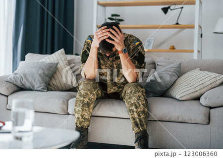 Having flashbacks. Post traumatic stress disorder. Soldier in uniform sitting indoors 123006360