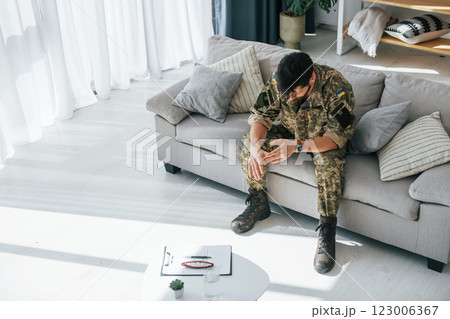 Bad mood. Post traumatic stress disorder. Soldier in uniform sitting indoors Bad mood. Post traumatic stress disorder. Soldier in uniform sitting indoors 123006367