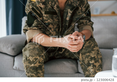 Close up view. Soldier in uniform is indoors in the domestic room 123006428