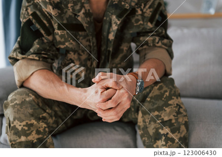 Close up view. Soldier in uniform is indoors in the domestic room 123006430