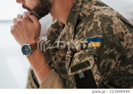 Ukrainian flag. Soldier in uniform is indoors in the domestic room 123006446
