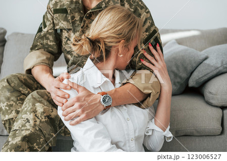 Soldier with his wife sitting indoors and embracing Soldier with his wife sitting indoors and embracing 123006527