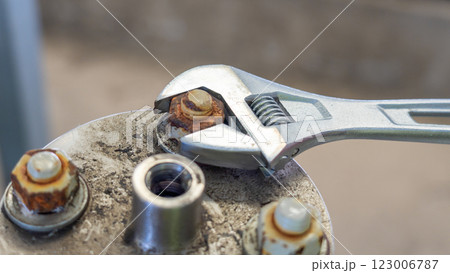 Adjustable wrench used to loosen a rusty bolt on a metal surface. 123006787