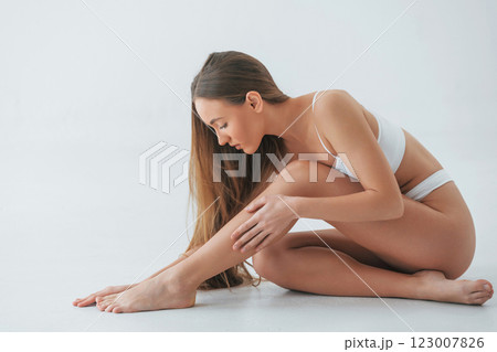 Sitting on the floor. Woman in underwear with slim body type is posing in the studio Sitting on the floor. Woman in underwear with slim body type is posing in the studio 123007826