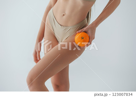 Holding orange fruit. Woman in underwear with slim body type is posing in the studio Holding orange fruit. Woman in underwear with slim body type is posing in the studio 123007834