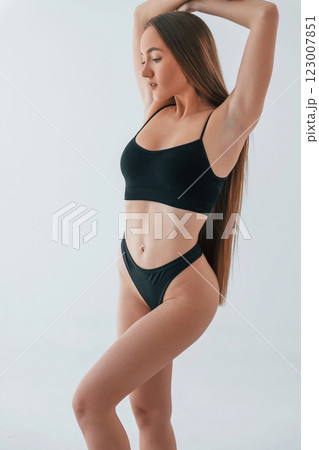 Standing in black lingerie. Woman in underwear with slim body type is posing in the studio 123007851