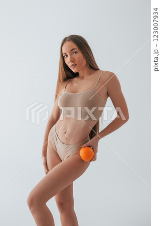 With orange and measuring tape. Woman in underwear with slim body type is posing in the studio With orange and measuring tape. Woman in underwear with slim body type is posing in the studio 123007934