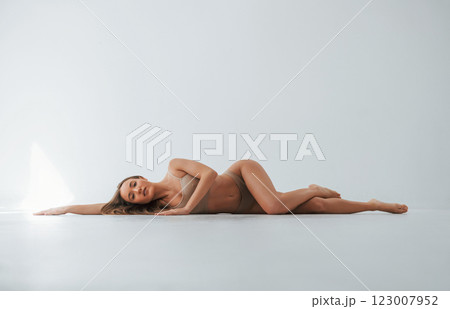 On the floor. Woman in underwear with slim body type is posing in the studio On the floor. Woman in underwear with slim body type is posing in the studio 123007952