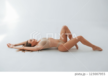 On the floor. Woman in underwear with slim body type is posing in the studio 123007955