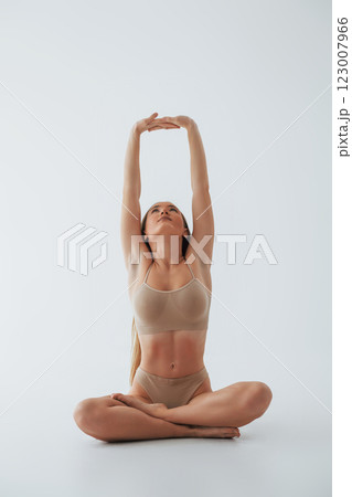 Doing yoga exercises. Woman in underwear with slim body type is posing in the studio Doing yoga exercises. Woman in underwear with slim body type is posing in the studio 123007966