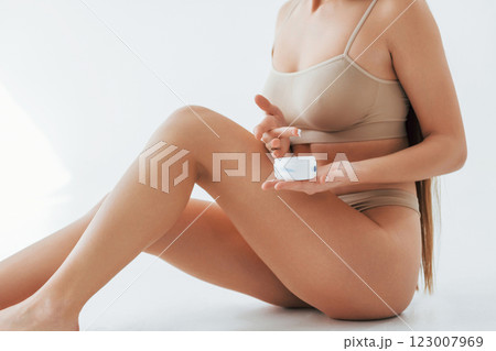 With cream. Woman in underwear with slim body type is posing in the studio With cream. Woman in underwear with slim body type is posing in the studio 123007969