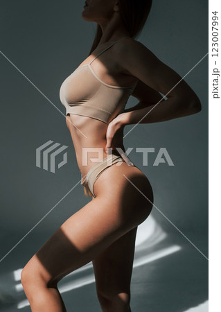 Sunlight through the windows. Woman in underwear with slim body type is posing in the studio Sunlight through the windows. Woman in underwear with slim body type is posing in the studio 123007994