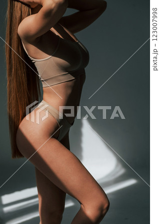 Sunlight through the windows. Woman in underwear with slim body type is posing in the studio 123007998