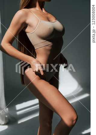 Beautiful sunlight and woman. Model in underwear with slim body type is posing in the studio 123008004
