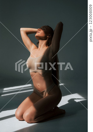 Enjoying sunlight. Woman in underwear with slim body type is posing in the studio Enjoying sunlight. Woman in underwear with slim body type is posing in the studio 123008009
