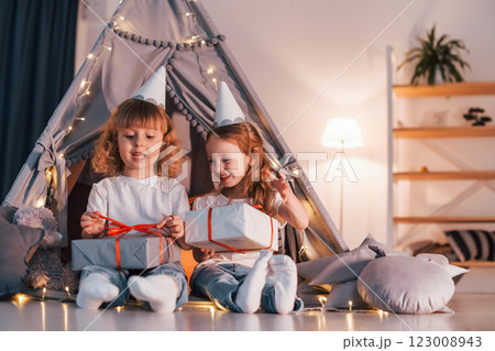 Holiday surprise. With gift boxes. Two little girls is in the tent in domestic room together Holiday surprise. With gift boxes. Two little girls is in the tent in domestic room together 123008943