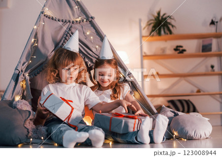 Holiday surprise. With gift boxes. Two little girls is in the tent in domestic room together 123008944