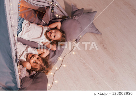 Laying down together. Two little girls is in the tent in domestic room Laying down together. Two little girls is in the tent in domestic room 123008950