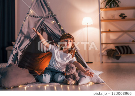 In aviator glasses. Cute little girl is in the tent in domestic room In aviator glasses. Cute little girl is in the tent in domestic room 123008966