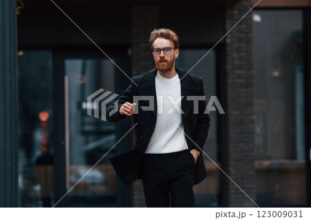 Running out of time. Stylish man with beard and in glasses is outdoors near building Running out of time. Stylish man with beard and in glasses is outdoors near building 123009031