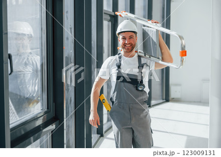 Holding ladder. Repairman is working indoors in the modern room Holding ladder. Repairman is working indoors in the modern room 123009131