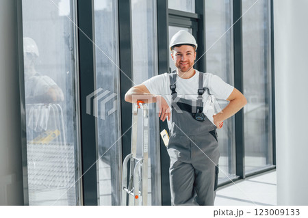 Smiling and posing. Repairman is working indoors in the modern room 123009133