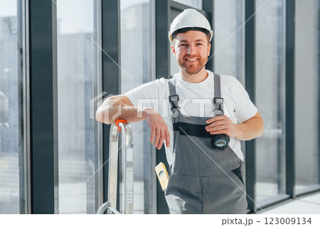 Smiling and posing. Repairman is working indoors in the modern room Smiling and posing. Repairman is working indoors in the modern room 123009134