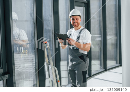 With notepad. Repairman is working indoors in the modern room 123009140