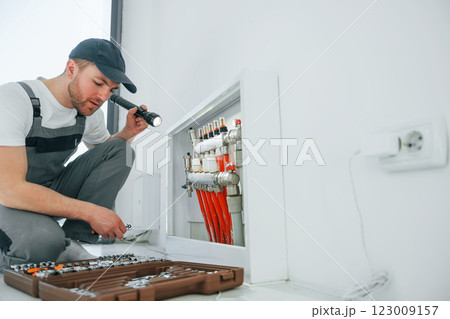 With special tools. Repairman is working indoors in the modern room With special tools. Repairman is working indoors in the modern room 123009157