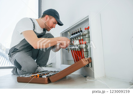 With special tools. Repairman is working indoors in the modern room With special tools. Repairman is working indoors in the modern room 123009159