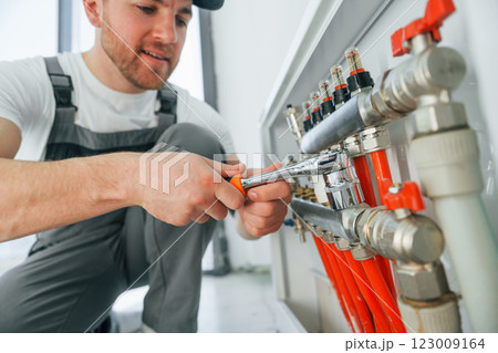 Working with pipes. Repairman is working indoors in the modern room 123009164
