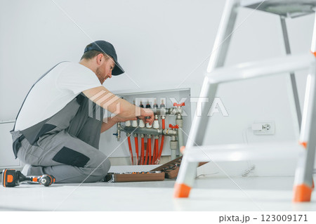 Side view. Repairman is working indoors in the modern room Side view. Repairman is working indoors in the modern room 123009171