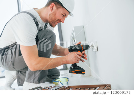 Side view. Repairman is working indoors in the modern room 123009175