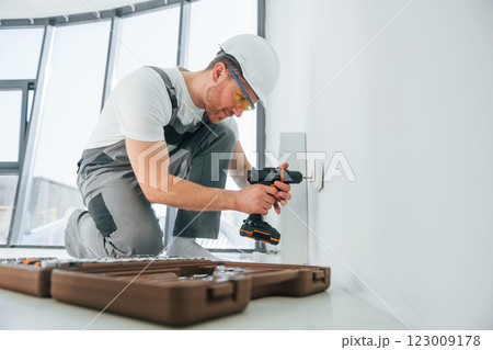 Side view. Repairman is working indoors in the modern room Side view. Repairman is working indoors in the modern room 123009178