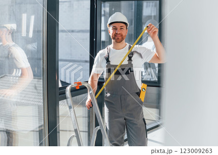 Holding measure tape. Repairman is working indoors in the modern room Holding measure tape. Repairman is working indoors in the modern room 123009263