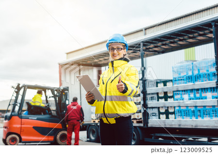 woman in front of forklift transporting goods from warehouse woman in front of forklift transporting goods from warehouse 123009525