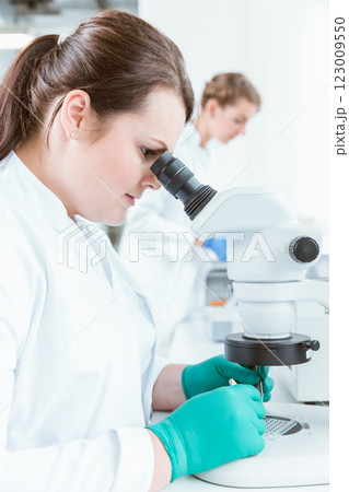 Female scientist using microscope in lab Female scientist using microscope in lab 123009550