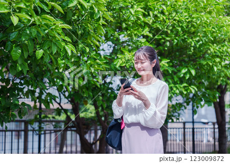 笑顔でスマホを見ながら歩く若い女性 笑顔でスマホを見ながら歩く若い女性 123009872