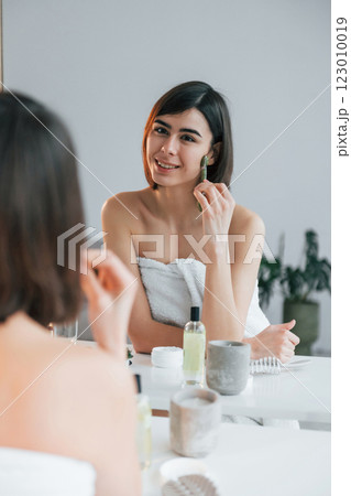 Cleaning face skin. Young woman is at home. Conception of beauty 123010019