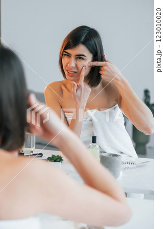 Squeezing the pimple. Young woman is at home. Conception of beauty Squeezing the pimple. Young woman is at home. Conception of beauty 123010020