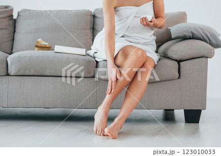 Using cream to clean legs skin. Young woman is at home. Conception of beauty 123010033