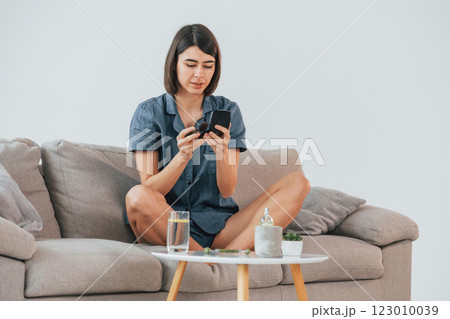 Sitting on the sofa and doing make up. Young woman is at home. Conception of beauty Sitting on the sofa and doing make up. Young woman is at home. Conception of beauty 123010039