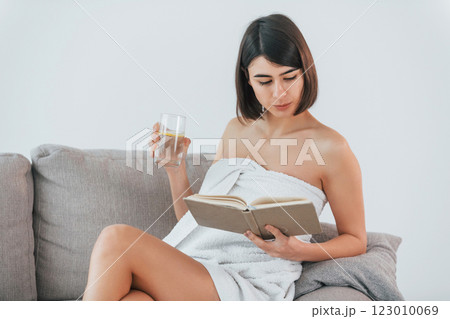 Sitting on the sofa. Young brunette is indoors against white background 123010069